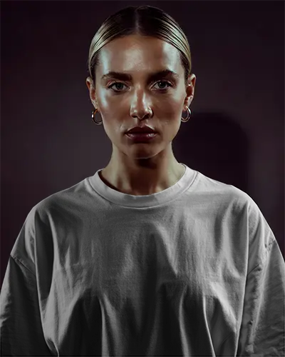 Dramatic Studio Tshirt Mockup Female Model With Bold Expression Dark Background And Spotlight Effect High Fashion Branding Shot