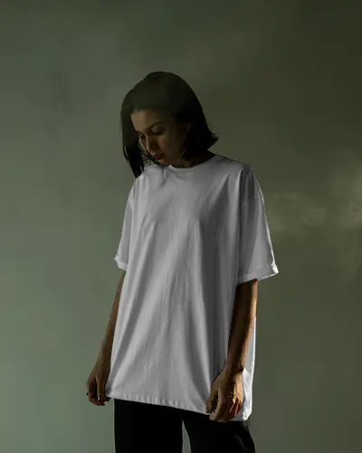 Moody Studio T Shirt Mockup Female Model Looking Down In Soft Smoky Lighting