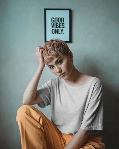 Urban Interior Tshirt Mockup Female Model With Short Hair Sitting Casually Under Good Vibes Frame