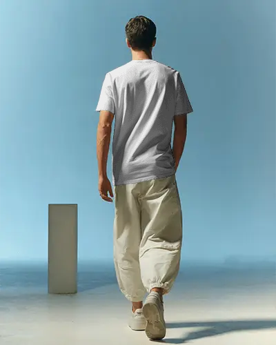 Back View Tshirt Mockup With Male Model Walking In Minimalist Pastel Studio Setting