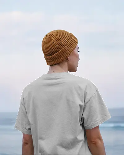 Tshirt Mockup Coastal Backdrop Person Wearing Beanie Facing Ocean In Soft Morning Light Relaxed And Serene Vibe