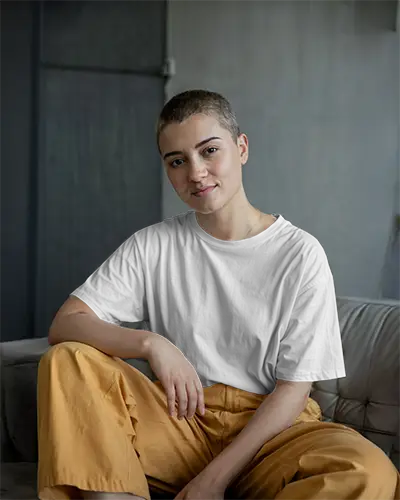 Tshirt Mockup Relaxed Female Model Sitting On Sofa In Loft Style Room Wearing White Shirt With Natural Lighting Casual Comfortable Ambience