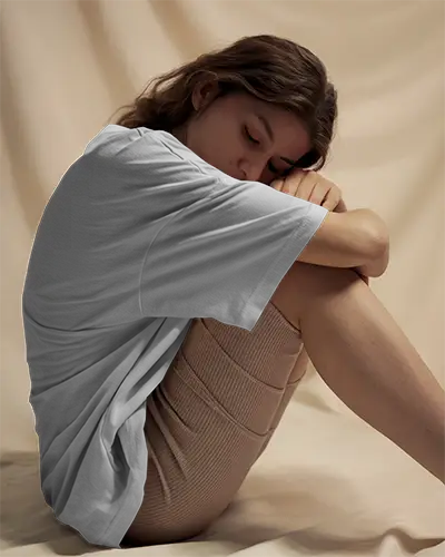 Tshirt Mockup Female Model Curled Up On Soft Beige Backdrop Wearing White Shirt In Cozy Lighting Serene And Intimate Atmosphere