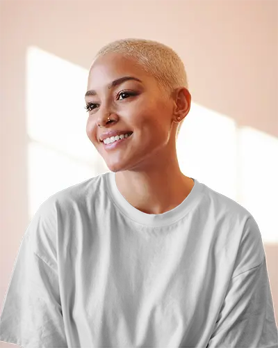 Sunlit Interior Tshirt Mockup Female Model Smiling In Soft Pink Light With Blonde Buzzcut Relaxed Casual Style