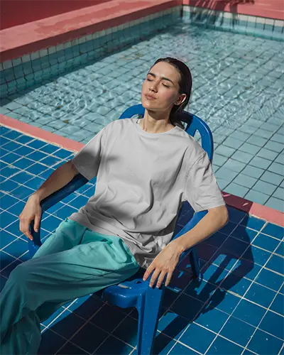 Poolside Tshirt Mockup Woman Sunbathing In Chair Blue Tiles Fresh Lighting Relaxed Summer Vibes