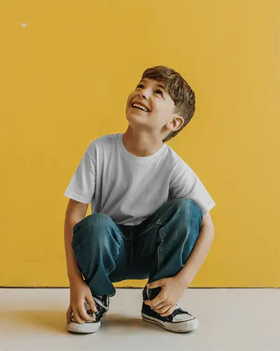 Vibrant Kidswear Tshirt Mockup Boy In Minimal Outfit Squatting And Smiling On White Floor