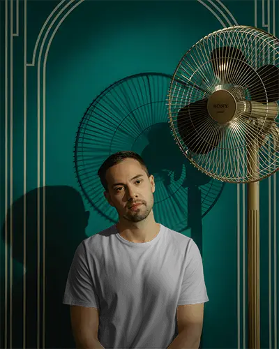 Moody Vintage Tshirt Mockup Male Model Standing In Retro Room With Electric Fan And Shadow Lines 02027