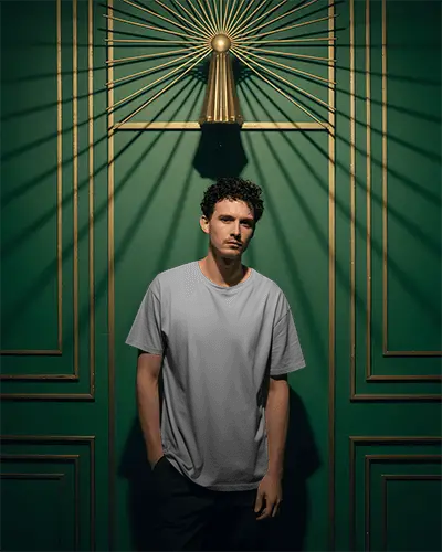 Vintage Styled Tshirt Mockup Model Under Sunburst Golden Deco On Rich Green Wall Paneling 02028
