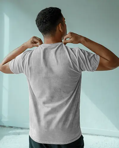 Indoor Natural Washed T Shirt Mockup Man Adjusting Collar In Soft Window Light Minimal Setting