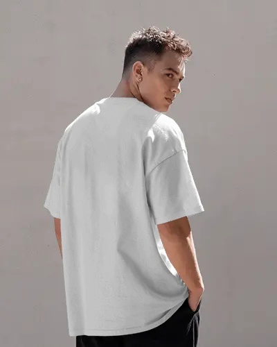 Back Facing T Shirt Mockup On Male Model Under Daylight Against Neutral Wall Texture