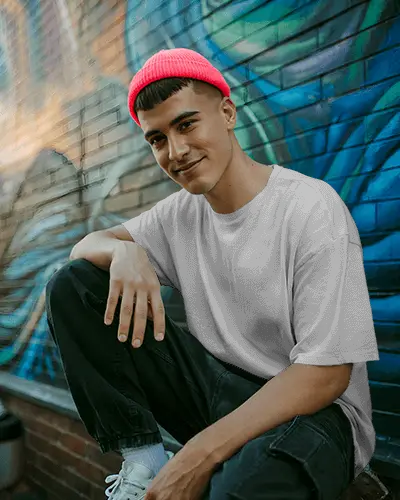 urban-streetwear-tshirt-mockup-man-in-pink-beanie-sitting-against-graffiti-wall