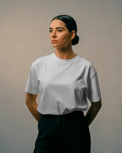 minimalist-studio-tshirt-mockup-female-model-standing-in-neutral-background-lighting