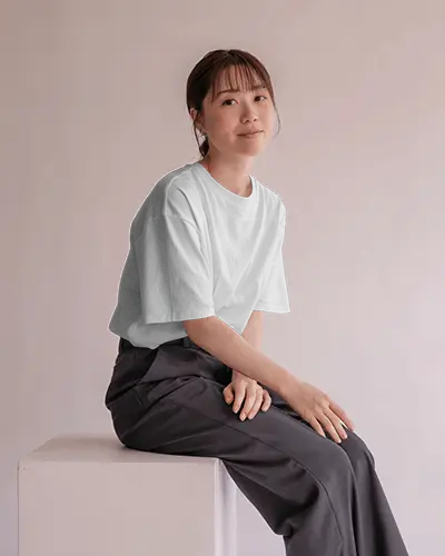 casual-elegance-t-shirt-mockup-female-model-seated-on-white-block-in-clean-pastel-studio-setting