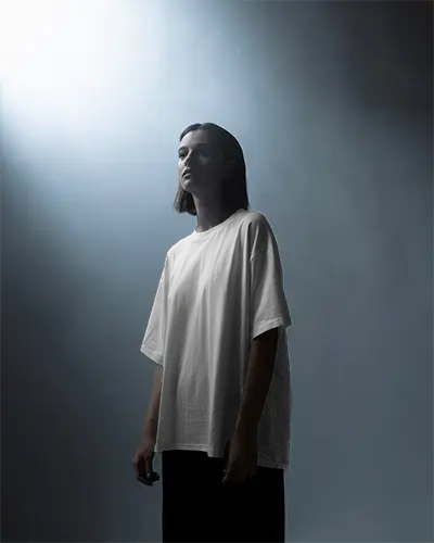 dramatic-studio-t-shirt-mockup-female-model-in-soft-spotlight-wearing-artistic-graphic-design