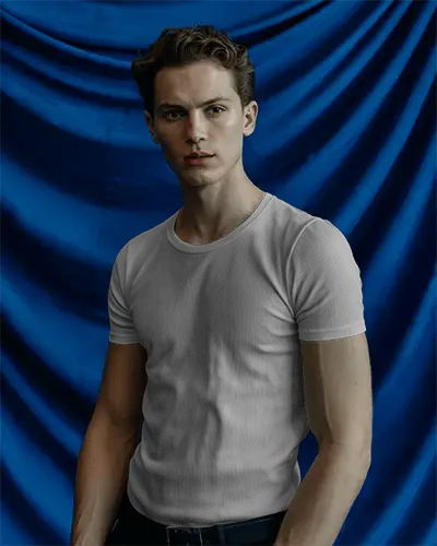 bold-backdrop-t-shirt-mockup-male-model-in-front-of-deep-blue-draped-fabric-studio-fashion