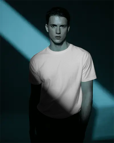 Cinematic T Shirt Mockup Male Model Standing In Dramatic Light Dark Studio Minimal Style