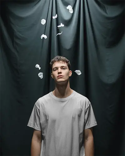 Creative T Shirt Mockup Male Model Under Falling Petals Dramatic Studio Editorial Look