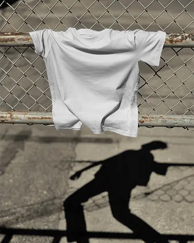 Industrial Shadow Tshirt Mockup Gray Tee Draped Over Metal Fence With Silhouette On Concrete Ground