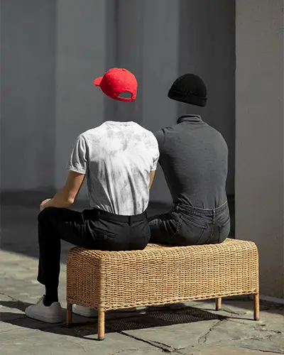 Acid Wash Tshirt Mockup Two Headless Men Sitting On Wicker Bench In Sunlight Wearing Modern Outfits