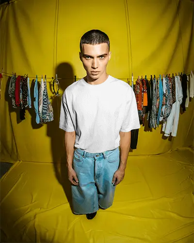 Vibrant Fashion Tshirt Mockup Male Model In Yellow Studio With Clothing Rack Background
