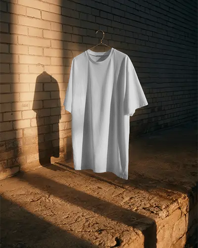 Rustic Sunset Tshirt Mockup Hanging On Brick Wall With Golden Hour Light And Long Shadow