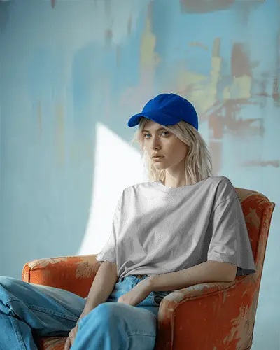 Minimalist Studio Tshirt Mockup Female Model In Blue Cap Sitting On Orange Chair