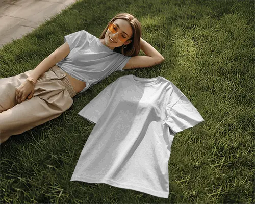 Outdoor Grass Tshirt Mockup Female Model Smiling In Sunlight With Shirt Laid Beside