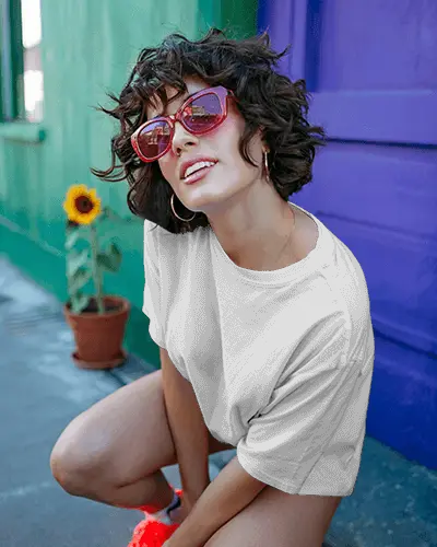Playful Tshirt Mockup Female Model With Curly Hair And Red Sunglasses Colorful Street Scene