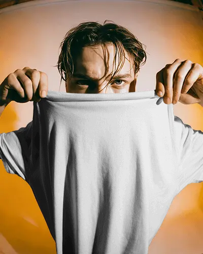 Dynamic Tshirt Mockup Male Model Holding Shirt Up With Intense Expression In Warm Light