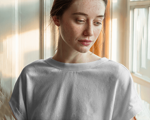 Sunlit Interior T Shirt Mockup Female Model Looking Down In Soft Warm Lighting Casual And Peaceful Ambience