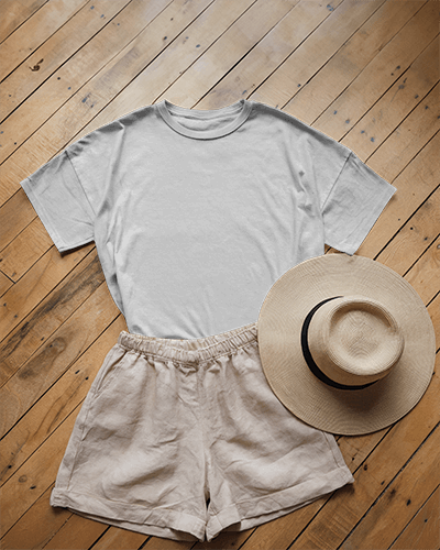 Flat Lay T Shirt Mockup On Wooden Floor With Summer Outfit Including Shorts And Straw Hat