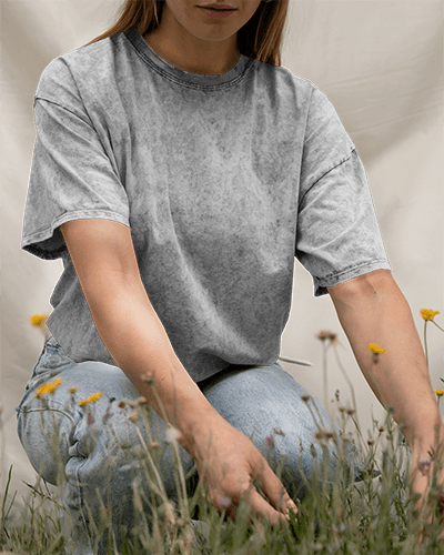 Acid Wash Outdoor T Shirt Mockup Female Model Kneeling In Wildflowers Vintage And Nature Inspired Look 0796