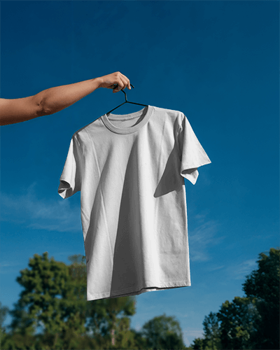 Clear Sky Outdoor T Shirt Mockup Hand Holding Hanger With White Tee In Bright Sunlight Crisp And Minimal Nature Backdrop 0809