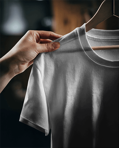 Moody Close Up T Shirt Mockup Hand Holding Round Neck Tee On Wooden Hanger Dramatic Lighting Cozy And Authentic Aesthetic 0840