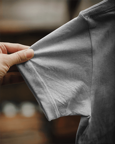 Close Up T Shirt Mockup Hand Stretching Distressed Fabric Texture Focused Soft Warm Lighting Authentic Vintage Style 0844