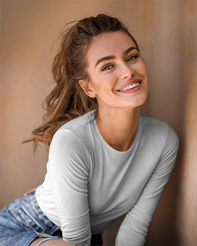 Sunlit Casual Long Sleeve Mockup Smiling Female Model Leaning Against Wall Wearing White Top And Denim Shorts Soft Natural Light With Warm Tones And Relaxed Vibe 0881