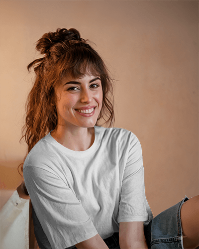 Casual Indoor T Shirt Mockup Female Model Smiling In Relaxed Pose Wearing White Round Neck Tee Against Warm Toned Background Natural And Friendly Vibe 0900