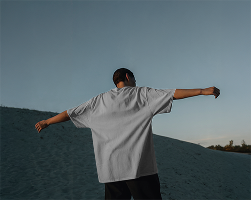 Sunset Dune Blank White Oversized T Shirt Mockup Male Model Arms Outstretched Minimal Scenic Backdrop