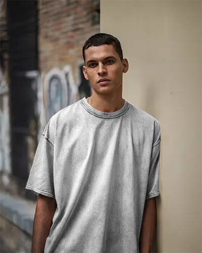 Streetwear Vibe Oversized Acid Wash White Tshirt Mockup On Man Leaning Against Wall