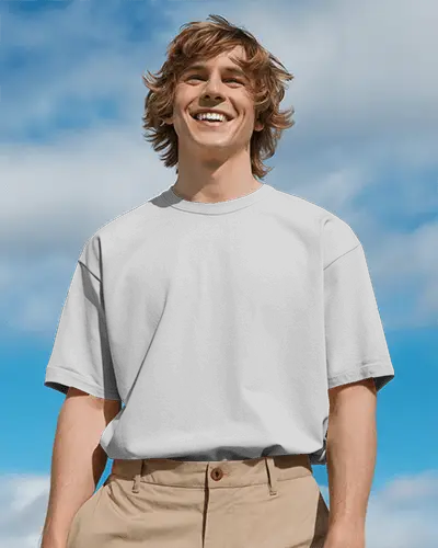 Outdoor Front View T Shirt Mockup Smiling Male Model In Boxy White Tee And Khakis Bright Sky Background Cheerful Casual Style