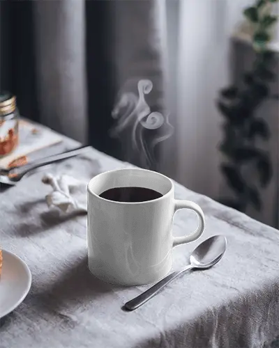 Serene Breakfast Mug Mockup White Coffee Cup With Design Space On Linen Tablecloth And Smoking Hot Drink Accented By Spoon And Natural Lighting Relaxing And Wholesome Atmosphere