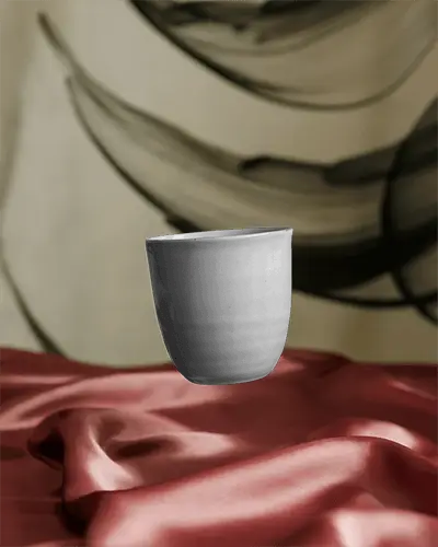 Minimalistic Ceramic Mug Floating Above Satin Fabric With Modern Abstract Art Backdrop