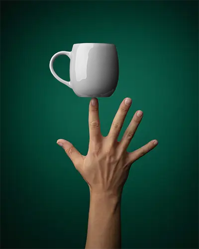 Ceramic Mug Mockup Balancing On Finger Isolated On Solid Background