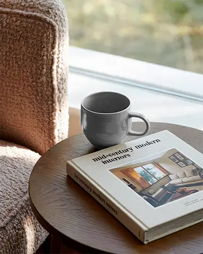 Elegant Ceramic Coffee Mug Mockup Next To Mid Century Interior Book On Table