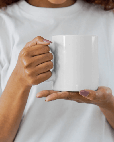 Hand Holding White Mug Mockup In Casual Setting With White Shirt