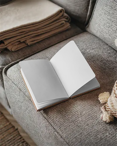 cozy-livingroom-open-notebook-mockup-on-textured-sofa-with-blankets-and-pillow-warm-and-inviting-home-setting-relaxed-and-comfortable-vibe