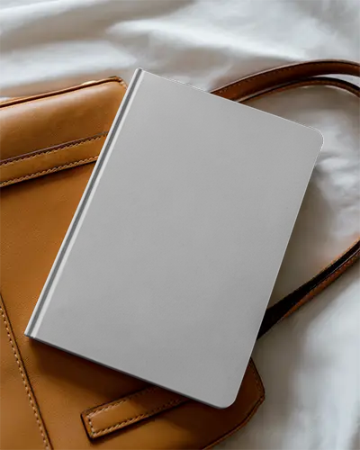 Hardcover Notebook Mockup With Soft Rounded Corners Placed On Leather Bag For Daily Use