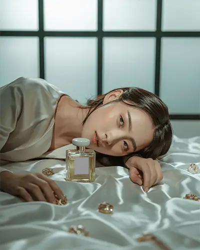 Elegant Perfume Mockup Female Model Lying On Satin Bed With Golden Bottle