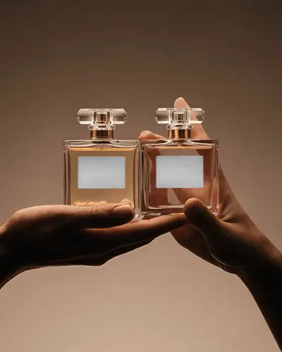 Hand Held Perfume Mockup Dual Glass Bottles Warm Beige Background Soft Studio Light