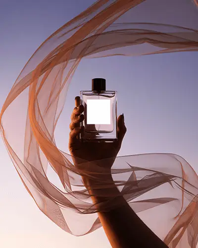 luxury-perfume-bottle-mockup-handheld-against-sunset-sky-with-flowing-sheer-fabric-elegant-scene